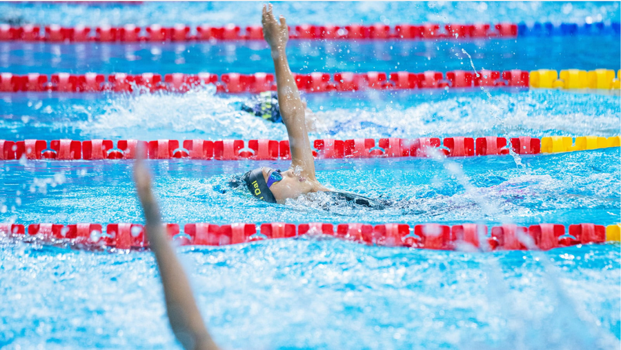 Woman wearing performance swimwear while performing backstroke swimming