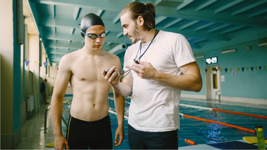 swim coach showing athlete data on the stopwatch on the side of the pool.